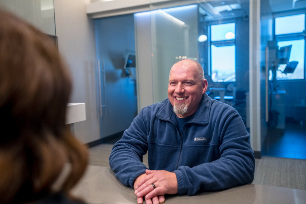 Man smiling at a woman across the desk in dental office.